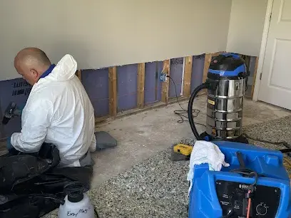 Wet drywall cut out and a dehumidifier running during a dry-out